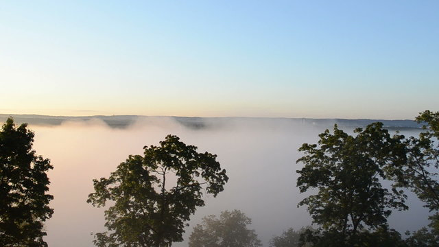 dence fog rises downhill river houses forest landscape distance