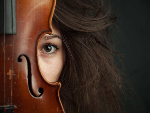Young Brunette Girl with violin in dark room