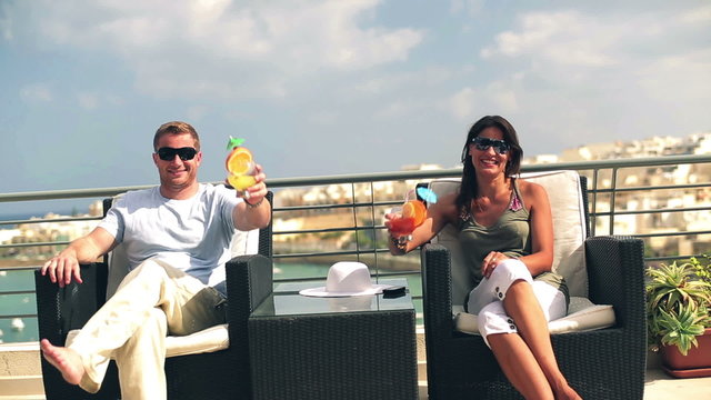 Happy couple with exotic drinks celebrating on the terrace, cran