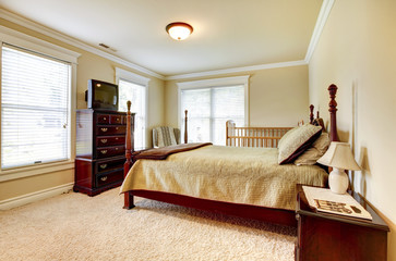 Large bright bedroom with wood furniture and beige tones.
