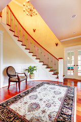 Entrance with curved staircase and luxury rug with chair.