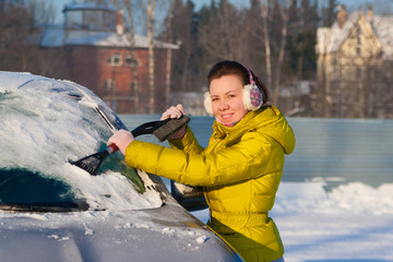 Girl cleaning car from snow