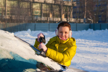 Girl cleaning car from snow