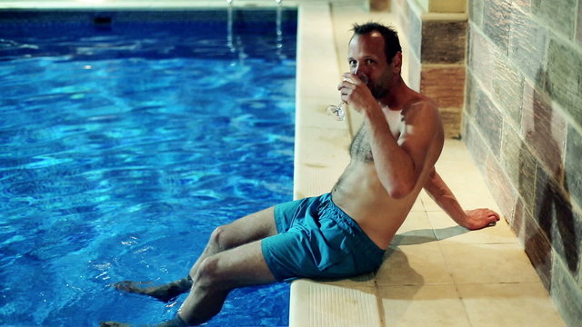 Portrait of smiling man drinking vine by the swimming pool at ni