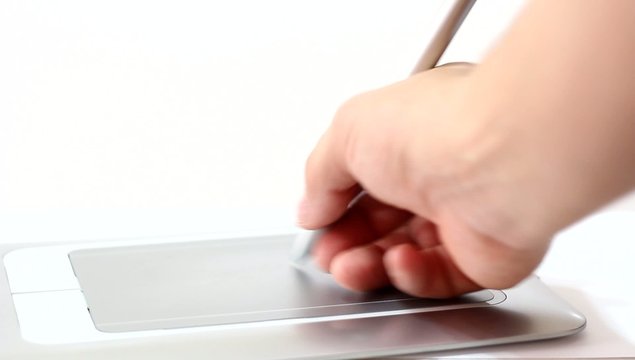 Man draws a pen on tablet lying on table close up