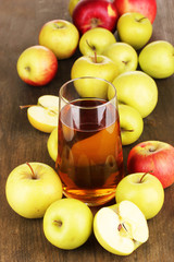 Useful apple juice with apples around on wooden table