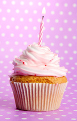 tasty birthday cupcake with candle, on violet background