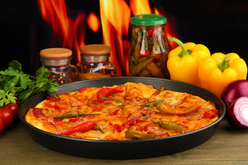 Tasty pepperoni pizza in pan with vegetables on flame