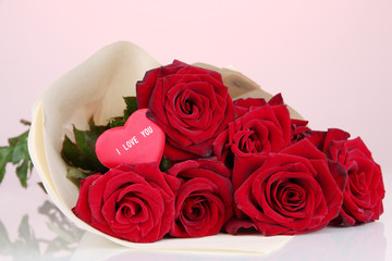 Beautiful bouquet of red roses with valentine on red background