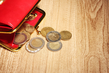 female red wallet with coins on wooden background