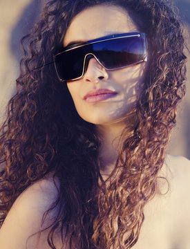 Young woman with curly hair wearing sunglasses