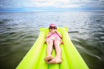 Little girl laying on tube swimming in the sea
