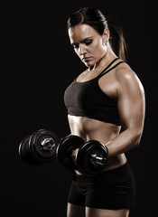 Beautiful fitness woman working out with dumbbells.