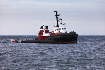 Obraz premium Tugboat floating in wait on calm ocean at anchor
