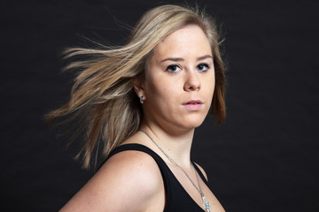 Pretty blonde girl against dark background. Studio shot.