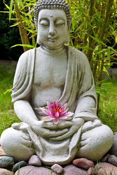 Buddha sculpture with lotus and bamboo leaves in background