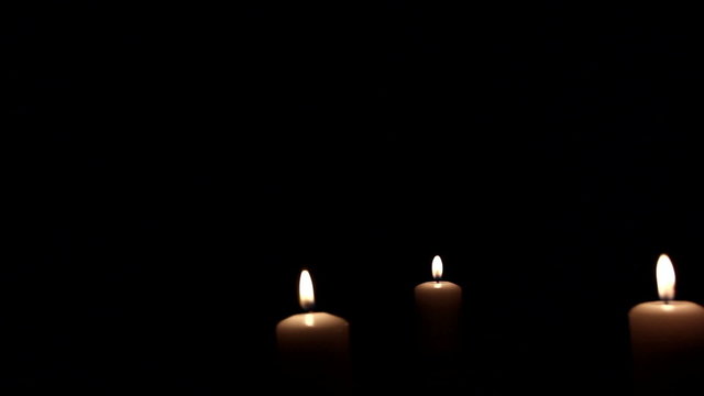 Three   burning candles in dark.