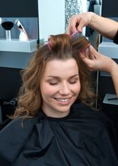 Fototapeta premium hair stylist curling woman hair in salon