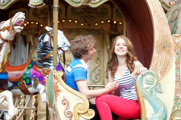Fototapeta na wymiar Happy young couple in an equipage of vintage Parisian merry-go-r
