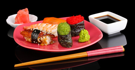 delicious sushi served on red plate isolated on black