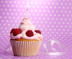 tasty birthday cupcake with candle, on violet background