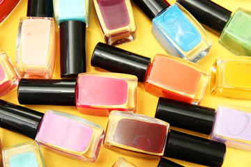 Group of bright nail polishes, on yellow background