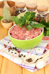 Bowl of raw ground meat with spices on wooden table