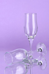 Two empty wine glasses on color background