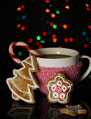 Cup of coffee with holiday candy on Christmas lights background