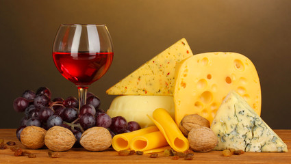 Various types of cheese on wooden table on brown background © Africa Studio