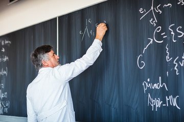 Senior chemistry professor writing on the board