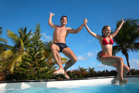 Young couple jumping in swimming pool - Powered by Adobe