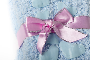 Pink gift bow on blue towels with heart shapes.