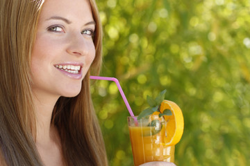 Junge Frau lächelt mit einem Glas Orangensaft