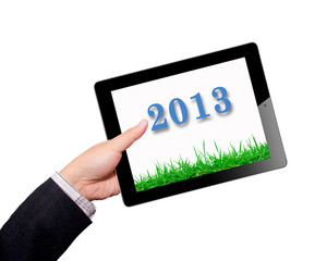 Hands with tablet computer screen grass in 2013 year. Isolated o