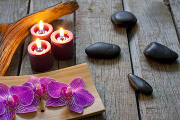 Spa stones orchids and candle on wooden boards