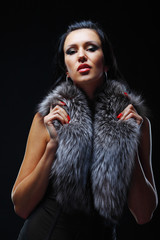 Fashion model posing in studio covering her neck in a fur