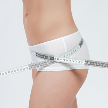 femme mesurant sa taille fine en boxer blanc