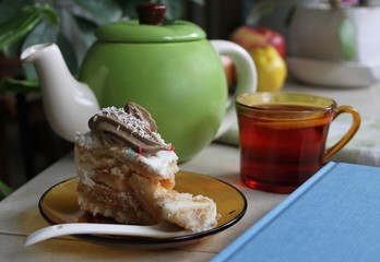 Still life with green kettle, cup of tea and cake