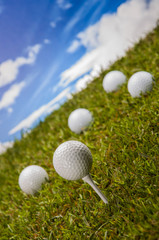 Golf balls, green grass, clouds background