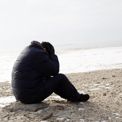 Lonely man sitting on sand