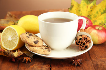 cup of hot tea and autumn leaves, on brown background