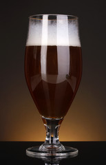 Glass of beer on brown background