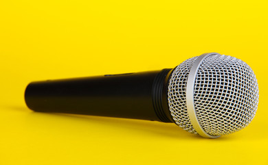 Black microphone on yellow background