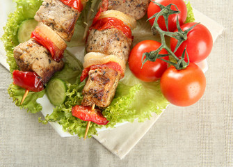 tasty grilled meat and vegetables on skewer on plate, on table