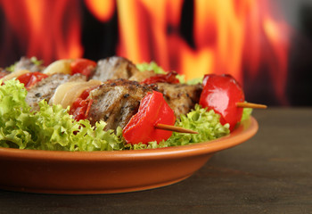tasty grilled meat and vegetables on plate, on fire background