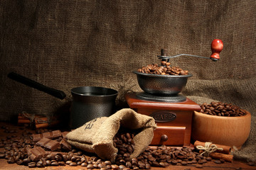 Coffee grinder, turk and cup of coffee on burlap background
