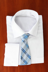 New white man's shirt with color tie on wooden background