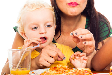 Child drinking juice and eating pizza