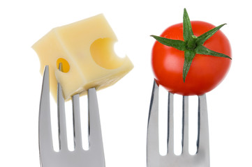 cheese and tomato on forks against white